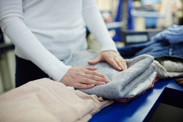 Working in dry-cleaning shop Woman folding clean clothes in dry-cleaning workshop dry cleaner stock pictures, royalty-free photos & images