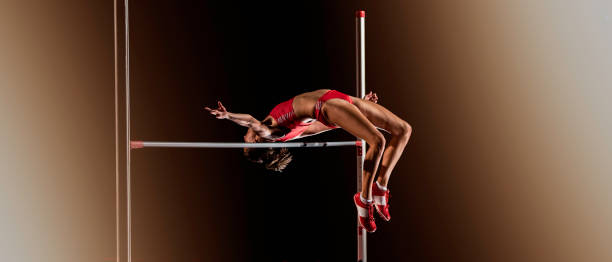 Woman jumping over a horizontal bar during high jump Rear view of a woman in mid air performing a high jump over a horizontal bar. high jump stock pictures, royalty-free photos & images