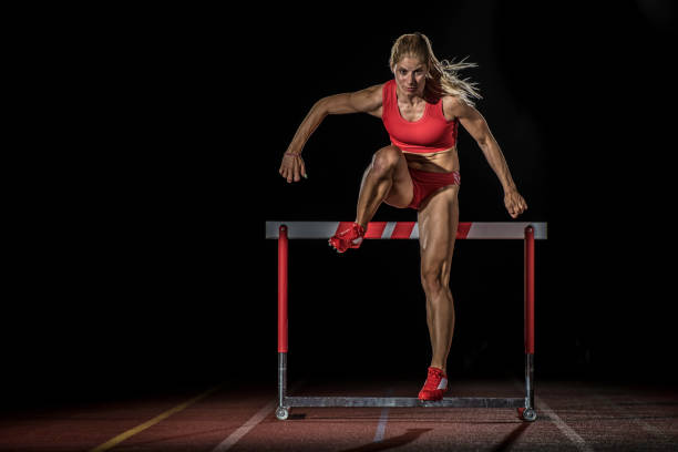 istock Female athlete jumping over a hurdle at night 656078842