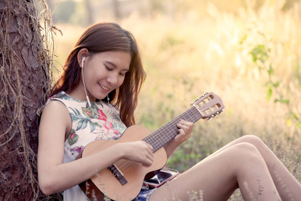 istock Young asian woman playing acoustic guitalele 656089320
