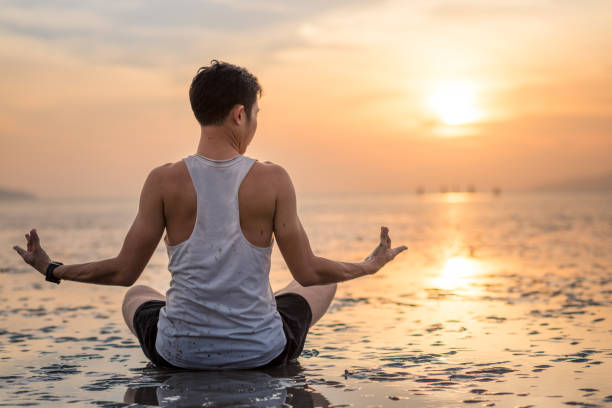 istock Young asian man doing yoga exercise at sunset beach 656092964