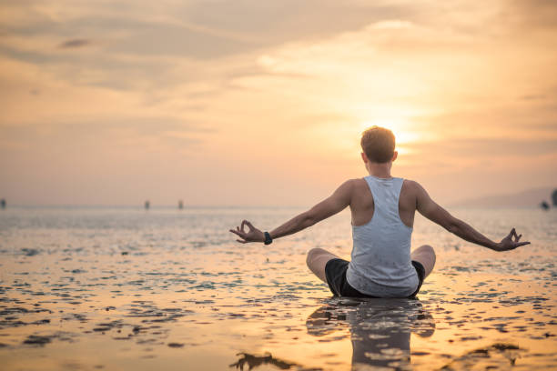 istock Young asian man doing yoga exercise at sunset beach 656093178