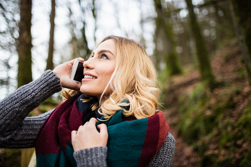 Beautiful woman talking on mobile phone in forest
