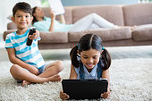 Boy watching television and girl using digital tablet in living room