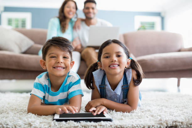 istock Siblings using digital tablet while lying on rug in living room at home 656094484