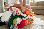 Girl packing overflowing suitcase for travel