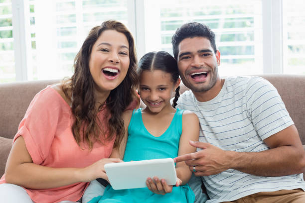 istock Parents and daughter using digital tablet in living room at home 656111946