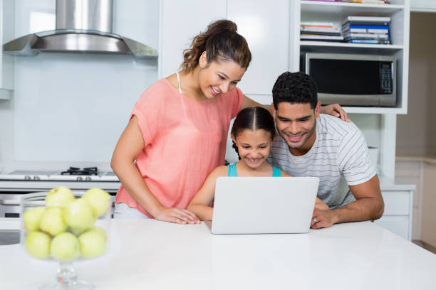 istock Parents and daughter using laptop in kitchen 656112010