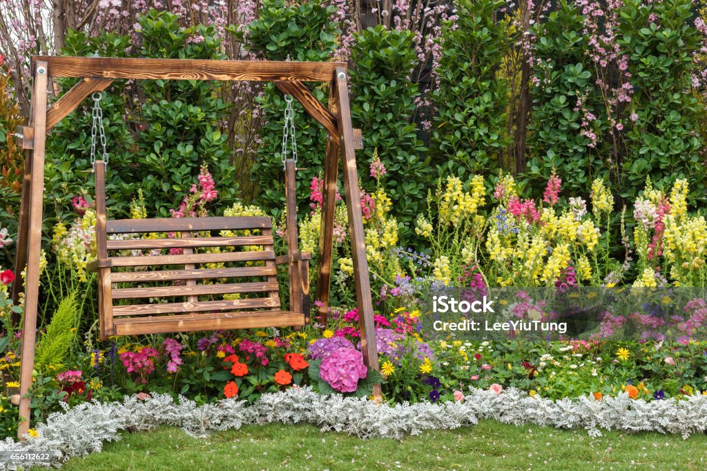 seat in flower garden Wooden swing seat in flower garden Yard - Grounds Stock Photo