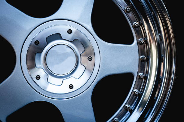 Consultant manager points to exhibition stand of new modern car rims. Selection of reliable aluminum car wheels concept