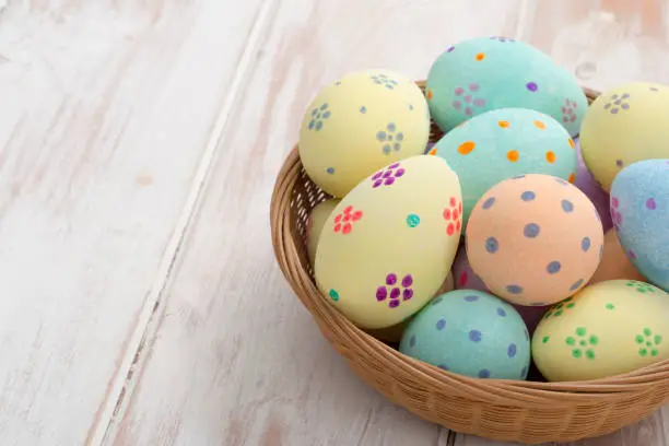Hand-painted easter eggs in a wicker bowl with copy space