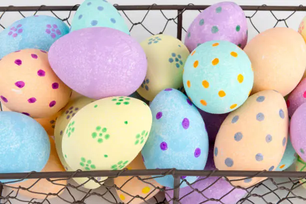 Close up of hand-painted pastel-colored eggs in a chicken wire basket