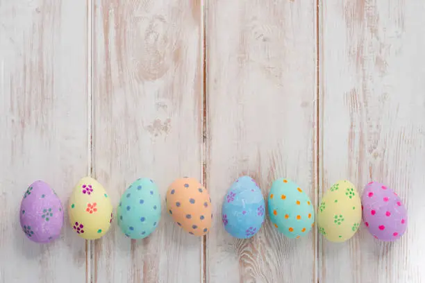 Banner photo of painted pastel easter eggs on wooden background copy space