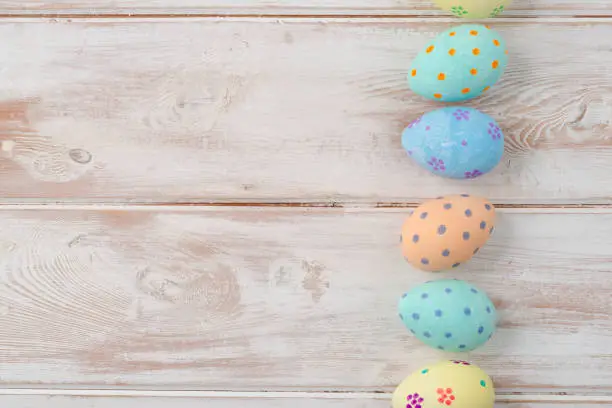 Hand-painted easter eggs arranged in a column on a wooden background with copy space