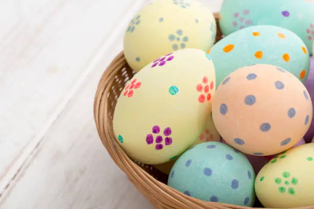 Close up of painted easter eggs in a wicker bowl with copy space