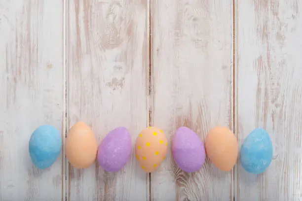 Banner photo of painted plain pastel-colored eggs on wooden surface with copy space