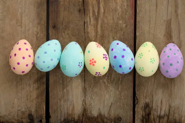 Pastel-colored easter eggs arranged in a row on a wooden background