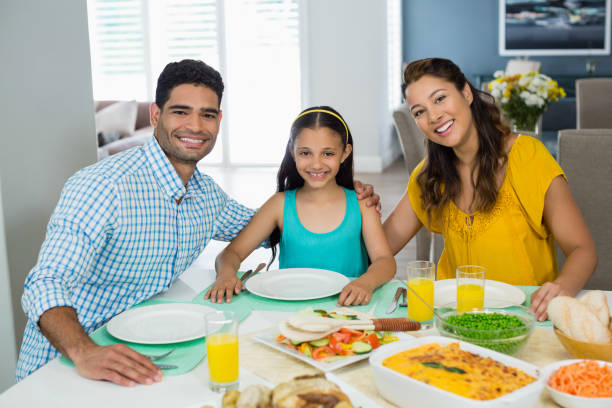 istock Daughter and parents having meal on table at home 656131006