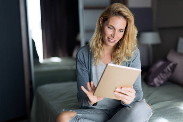 istock Beautiful blond woman relaxing on bed abd using tablet 656136166