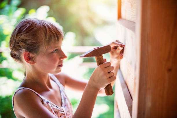 Little girl hammering a nail Little girl aged 9 hammering a nail to the wooden cabin wall.
girl with a hammer stock pictures, royalty-free photos & images
