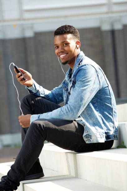 istock handsome man sitting on steps with phone and headphones 656164498
