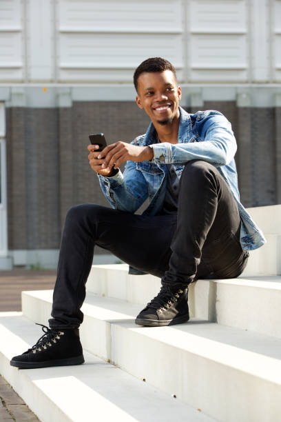 istock happy african man sitting on steps outside holding smart phone 656164574