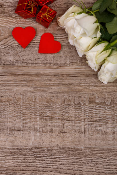 istock White roses with hearts on wooden background. 656169702