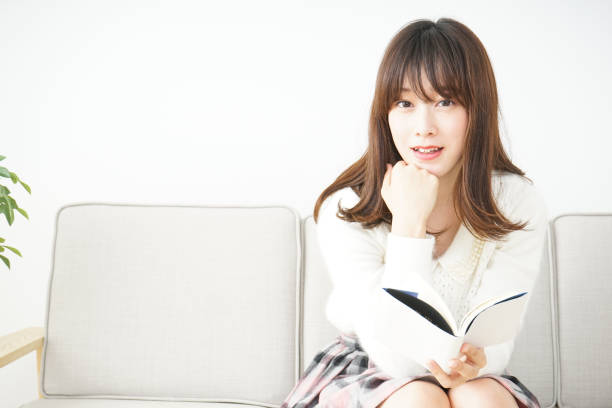 istock Young woman reading a book at home 656185380