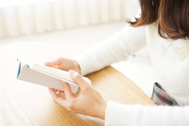 istock Young woman reading a book at home 656186432