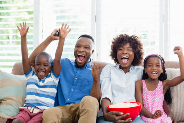Excited family and kids watching television while having popcorn in living room Family and kids watching television while having popcorn in living room at home popcorn snack bowl isolated stock pictures, royalty-free photos & images