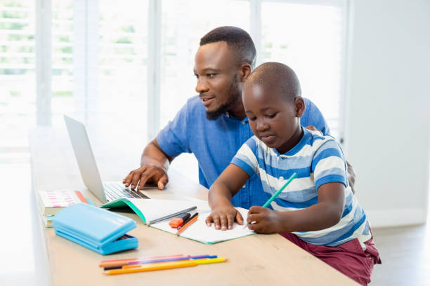 istock Father using laptop and son doing his homework in living room 656207846