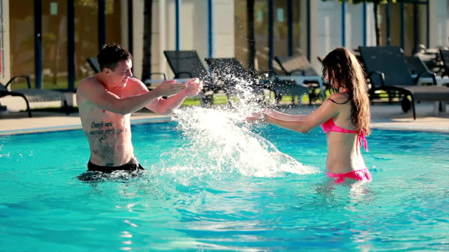 Young couple are splashing the water in the swimming pool