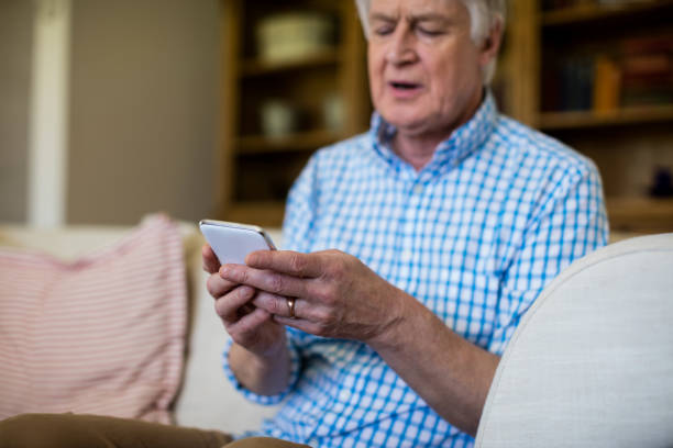 istock Senior man using mobile phone in living room 656214272