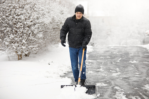 A man shoveling snow during a snow storm.
