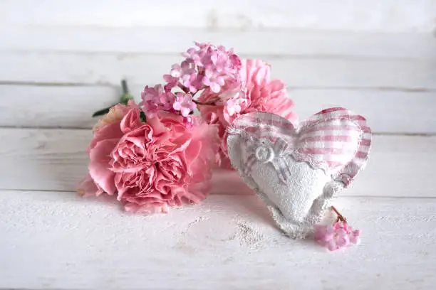 Still life with pink carnations and a heart in vintage style for mothers day and easter