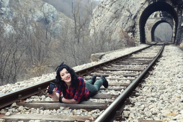 Photo of Teenager girl lying on a railway and making selfie with mobile phone