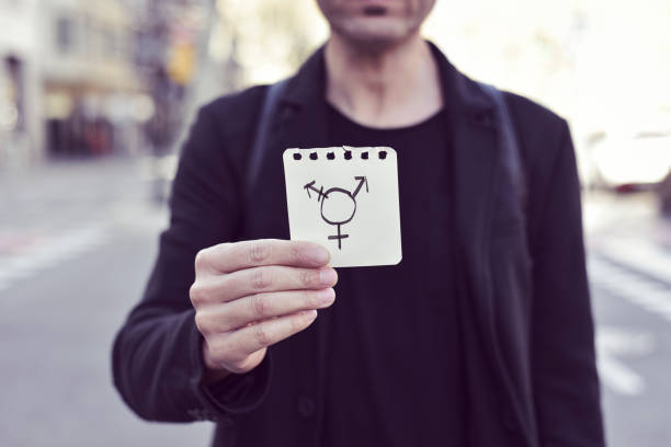 closeup of a young Caucasian man in the street showing a piece of paper with a transgender symbol drawn in it