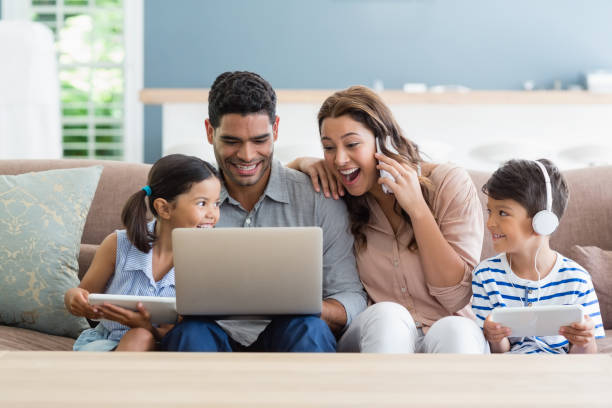 eltern und kinder mit laptop und digital-tablette im wohnzimmer - living room people joy happiness stock-fotos und bilder