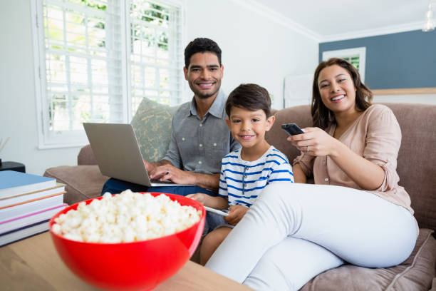 Mother watching television while father and son using laptop and digital tablet at home Portrait of mother watching television while father and son using laptop and digital tablet at home popcorn snack bowl isolated stock pictures, royalty-free photos & images