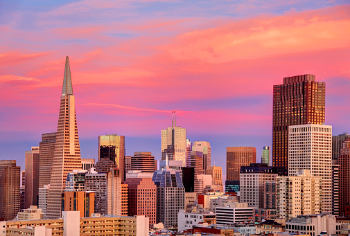 San Francisco, California skyline at sunset. On the  middle is the The Transamerica Pyramid the tallest skyscraper in the San Francisco skyline. In the background is the Francisco–Oakland Bay Bridge. San Francisco is a popular tourist destination known for its landmarks including the Golden Gate Bridge and cable cars.
