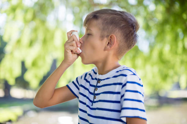 junge mit asthma-inhalator im park - asthmatic child asthma inhaler inhaling stock-fotos und bilder