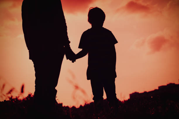 istock silhouette of father and son holding hands at sunset 656263304