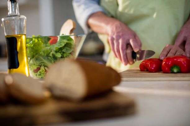 istock Senior man helping woman to cut vegetable in kitchen 656268168