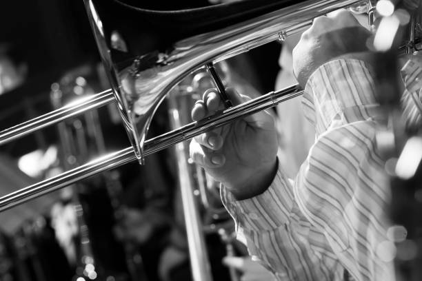Hands musician playing the trombone in the orchestra closeup in black and white