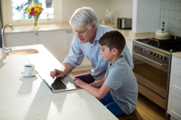 wnuk za pomocą laptopa z dziadkiem - grandparent using computer laptop dining table zdjęcia i obrazy z banku zdjęć