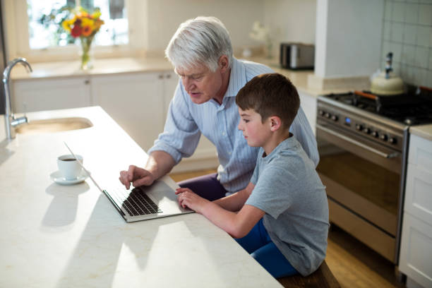 grandson using laptop with grandfather - grandparent using computer laptop dining table imagens e fotografias de stock