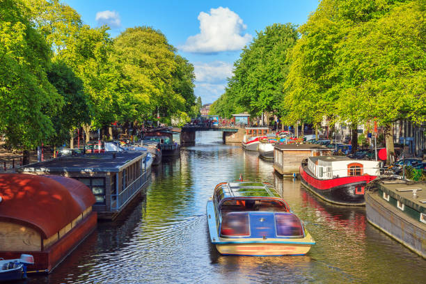Boat tour Amsterdam Beautiful vibrant image of a tourist canalboat on the famous canals of Amsterdam in summer houseboat photos stock pictures, royalty-free photos & images
