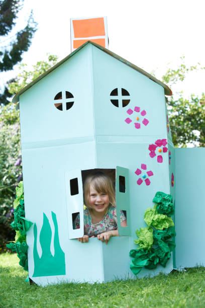Little Girl Playing In Home Made Cardboard House Little Girl Playing In Home Made Cardboard House playhouse stock pictures, royalty-free photos & images