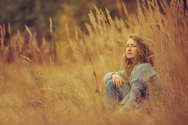 istock young girl sitting in the tall yellow grass 656278792
