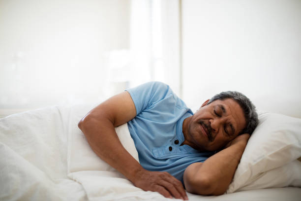 Senior man resting on bed in bedroom Senior man resting on bed in bedroom at home man sleeping on bed stock pictures, royalty-free photos & images